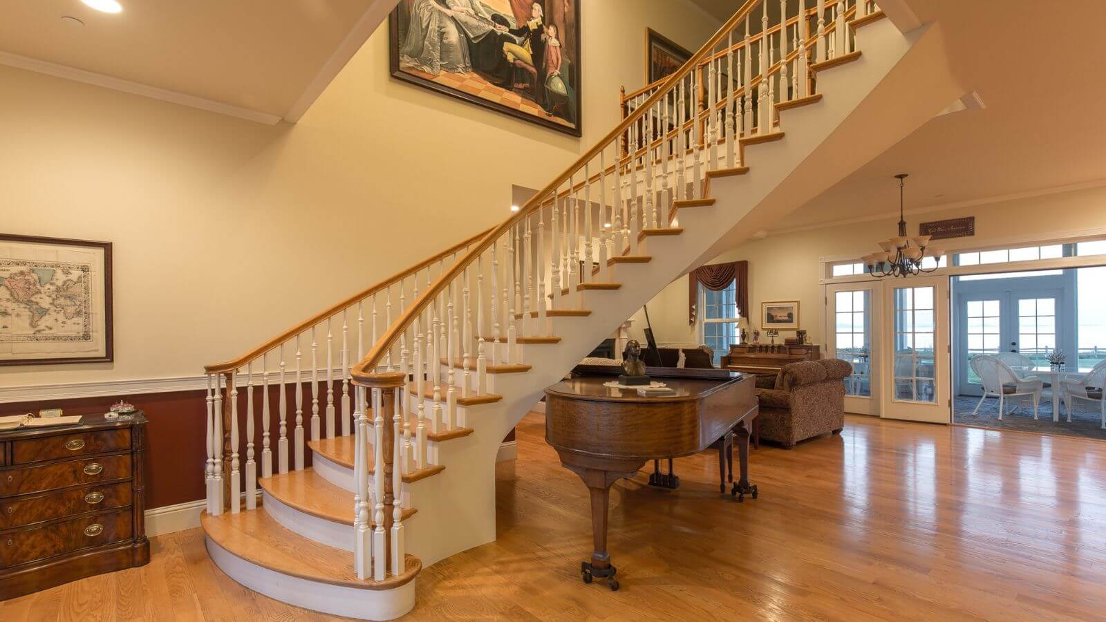 spiral staircase with oak steps and railings, large room with hardwood floors, wood grand piano, couch leading to enclosed patio